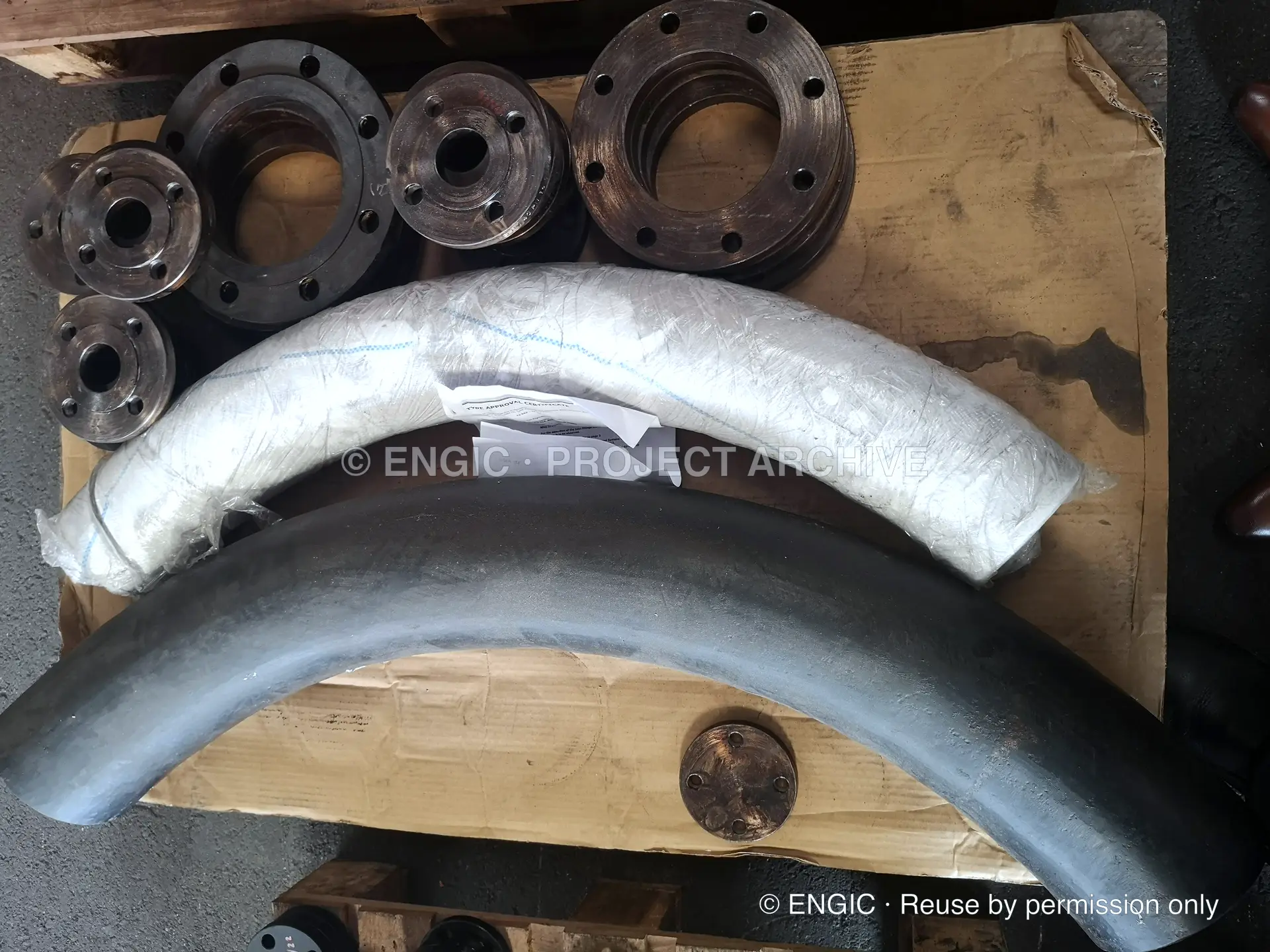 Wrapped pipe elbows beside flanges in a timber crate