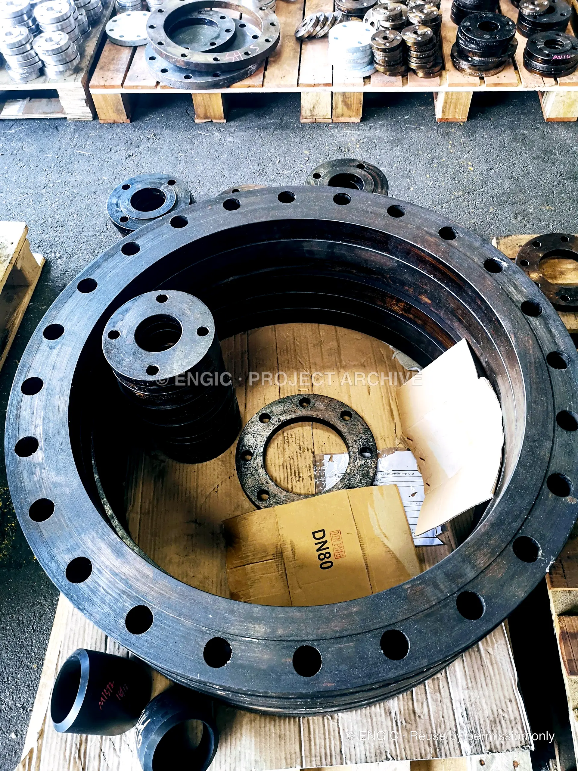 A large drilled flange ring beside a timber crate