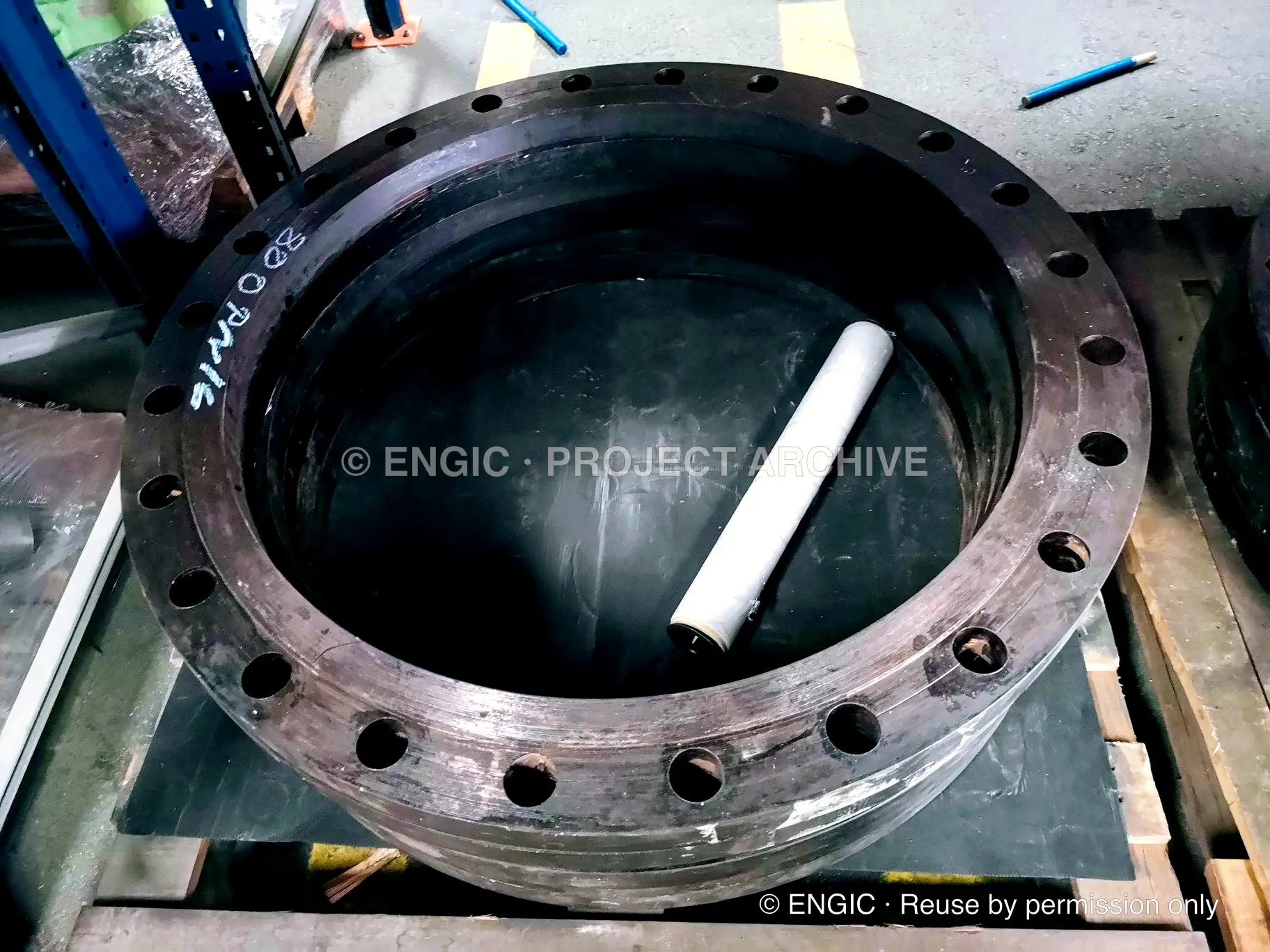 A close view into a stack of large-bore flanges with machined faces
