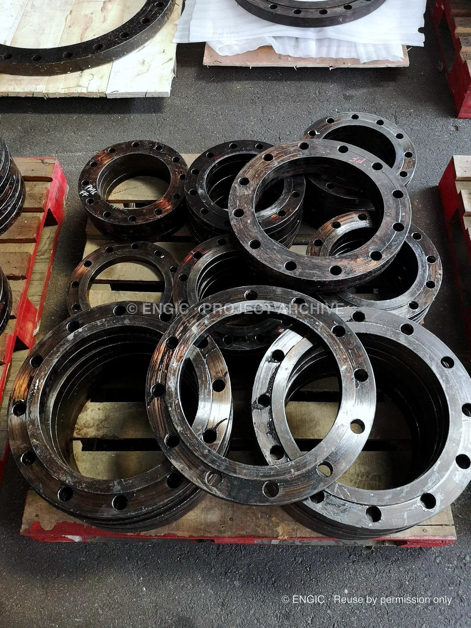 Large-bore flange rings stacked on a pallet, machined faces and drilled bolt circles visible
