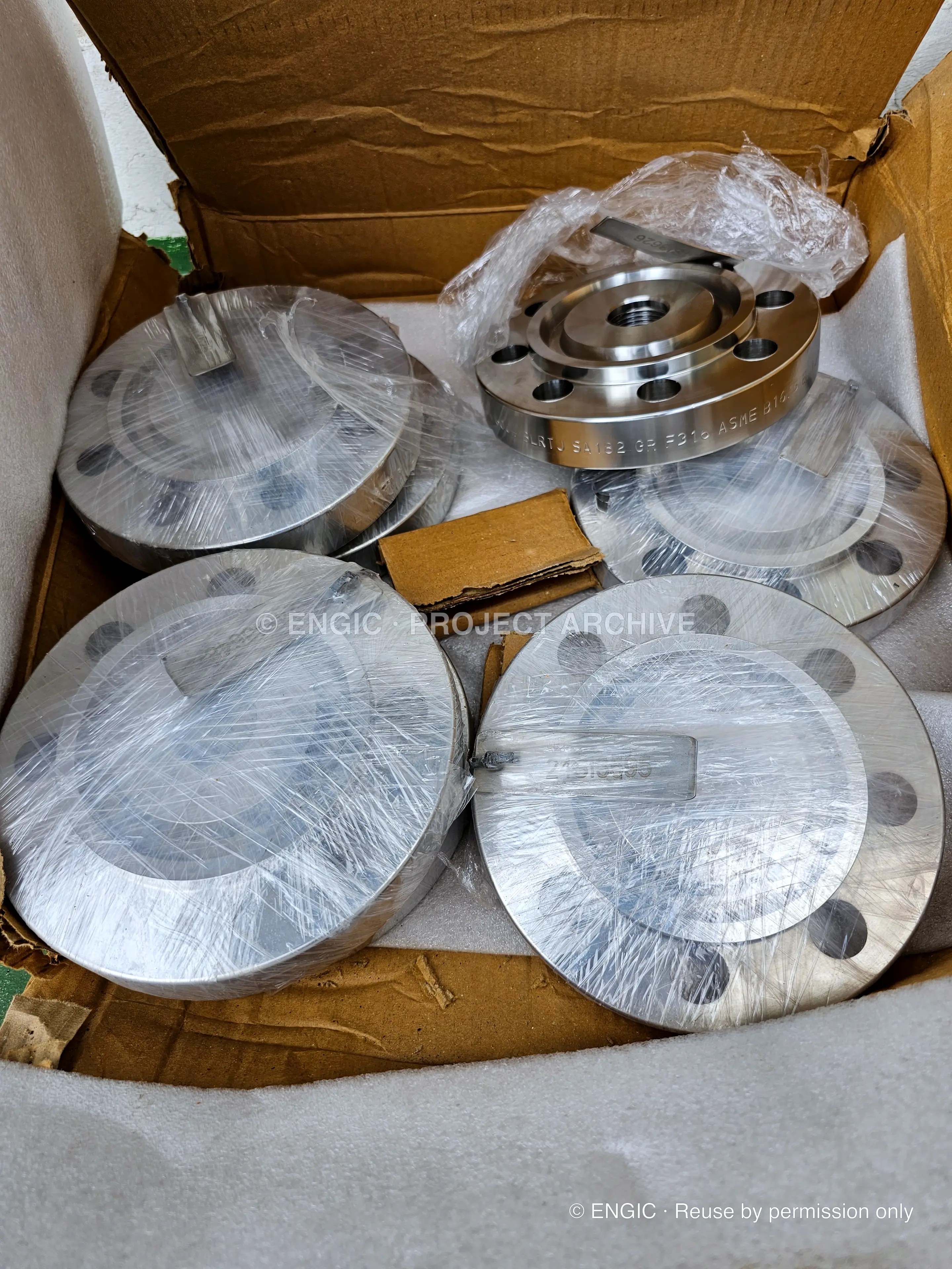 Bright-machined blind flanges and a raised-face flange packed in a box for despatch