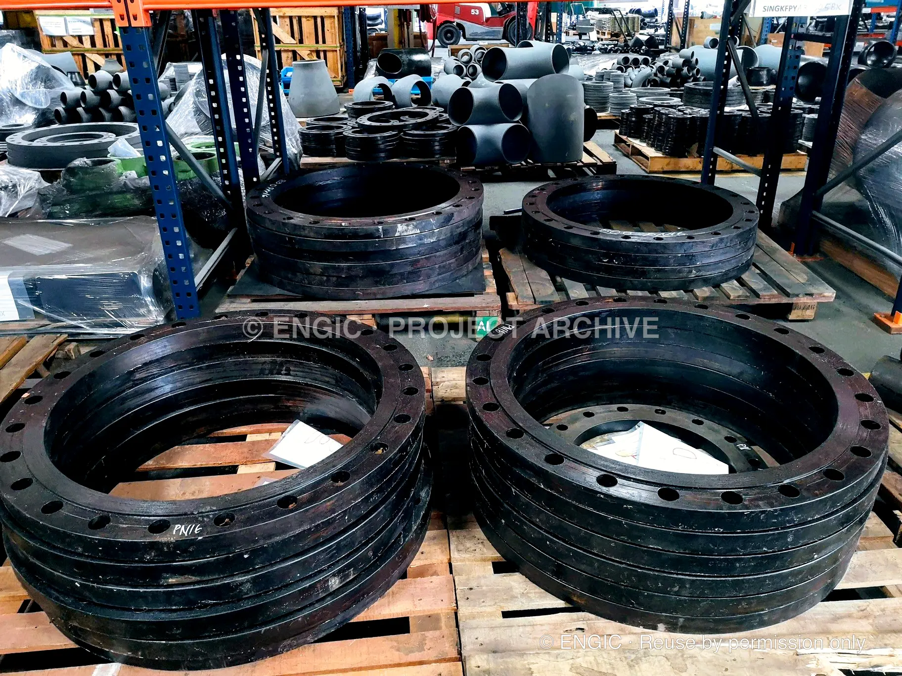 Large dark flange rings arranged on pallets in a yard