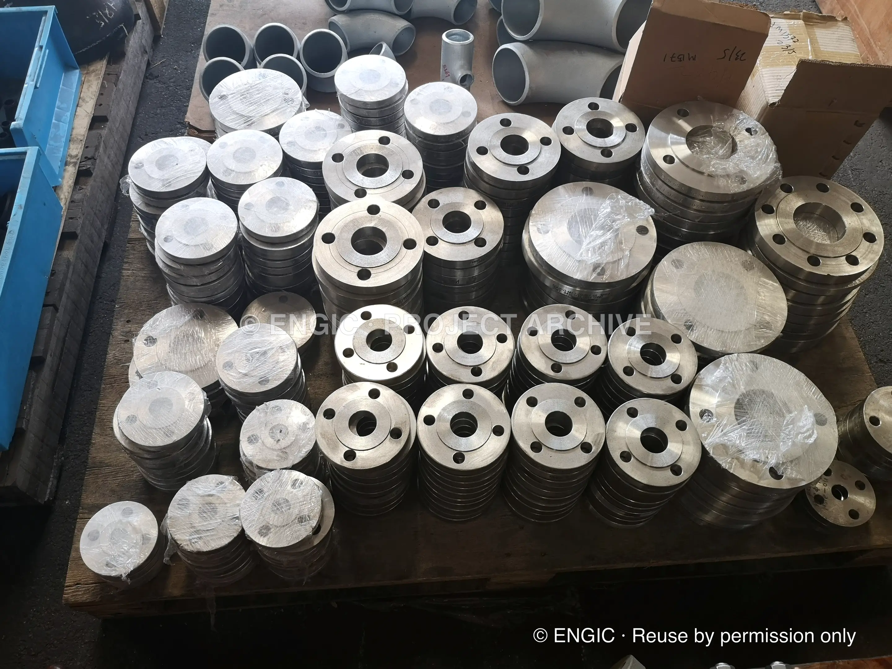 Small-bore stainless flanges sorted by size across pallets