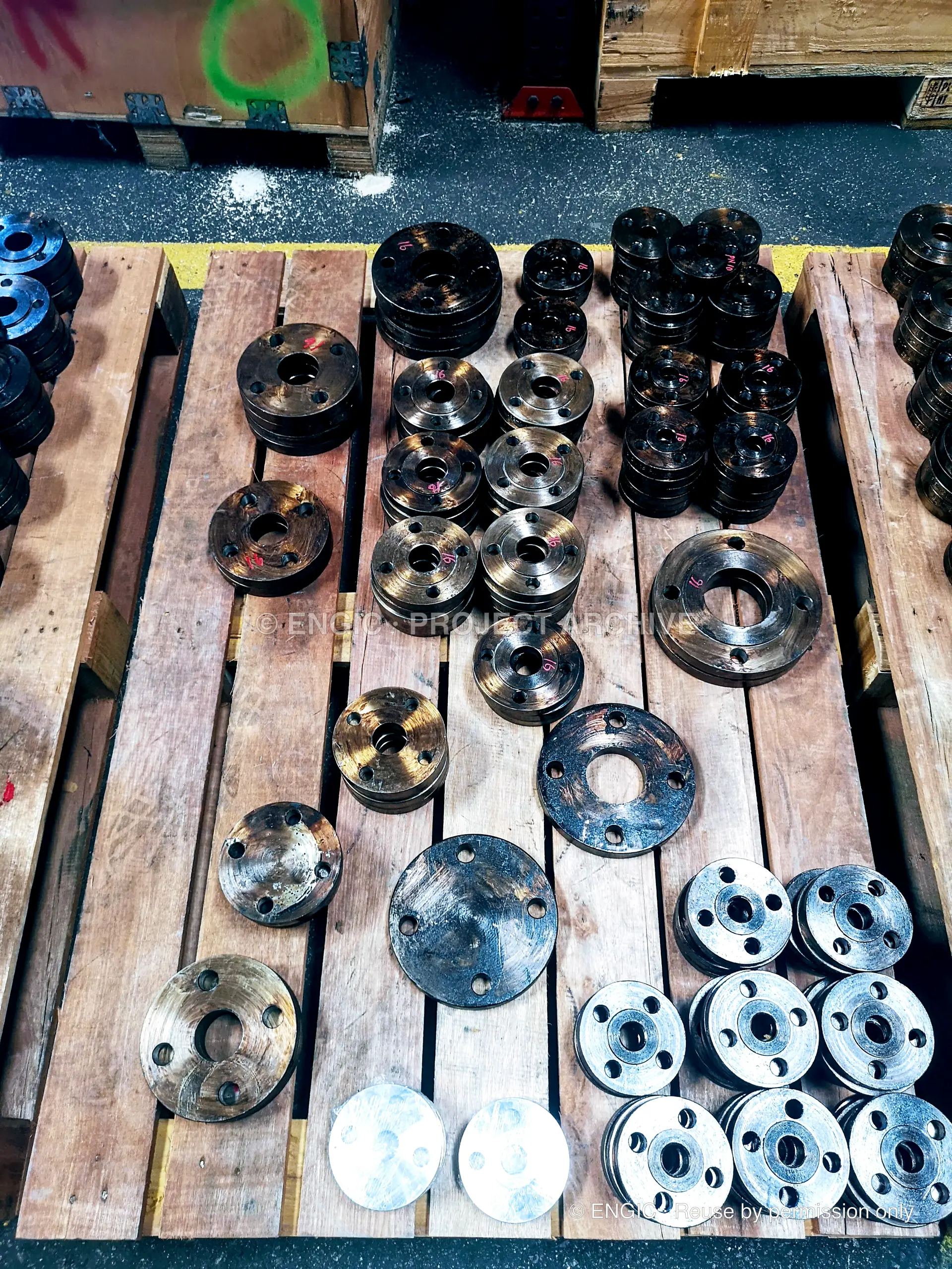 Small flanges of different sizes and finishes arranged across a timber pallet