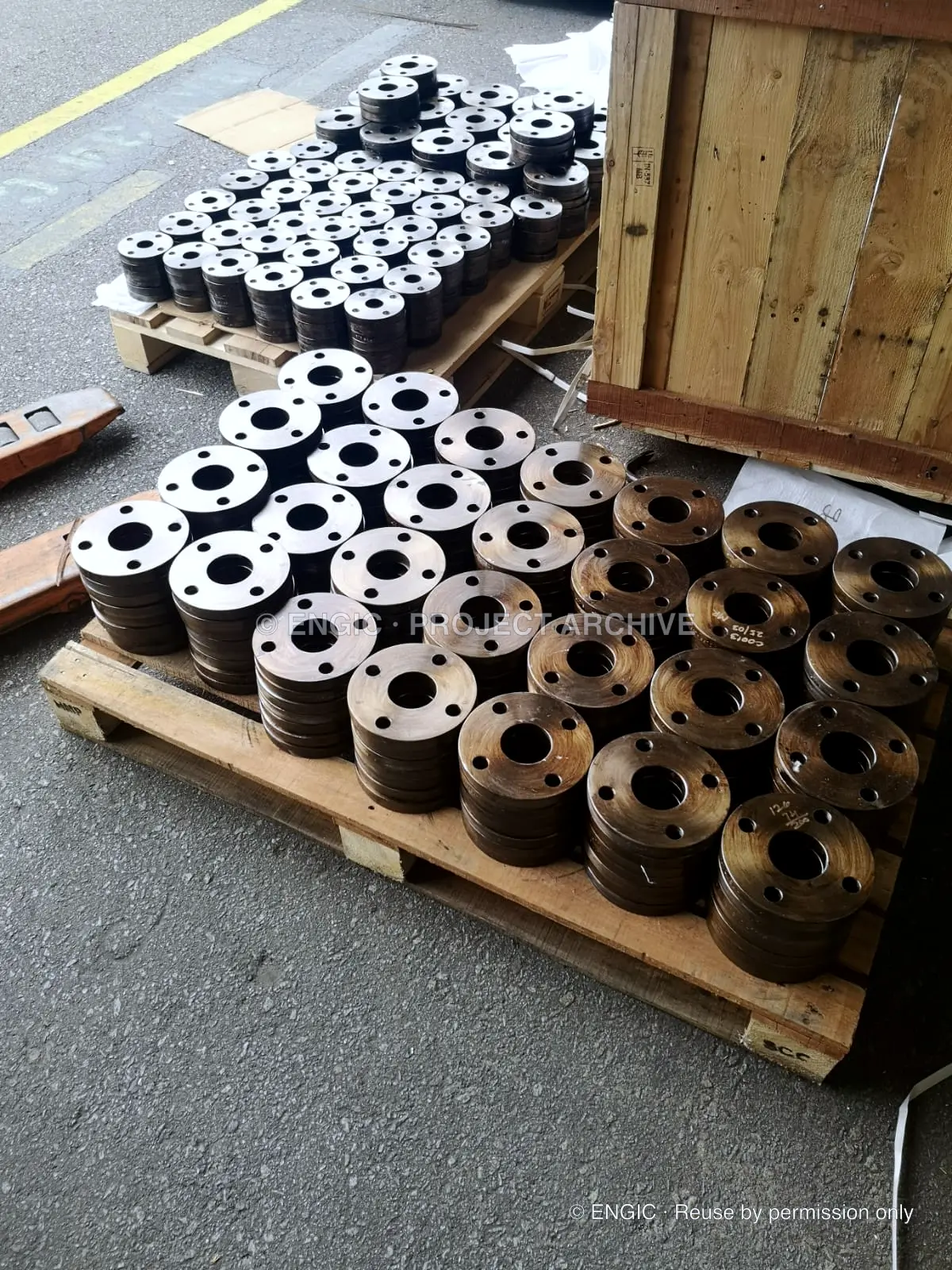 Small flanges in graduated sizes set out in rows across a timber pallet in the yard