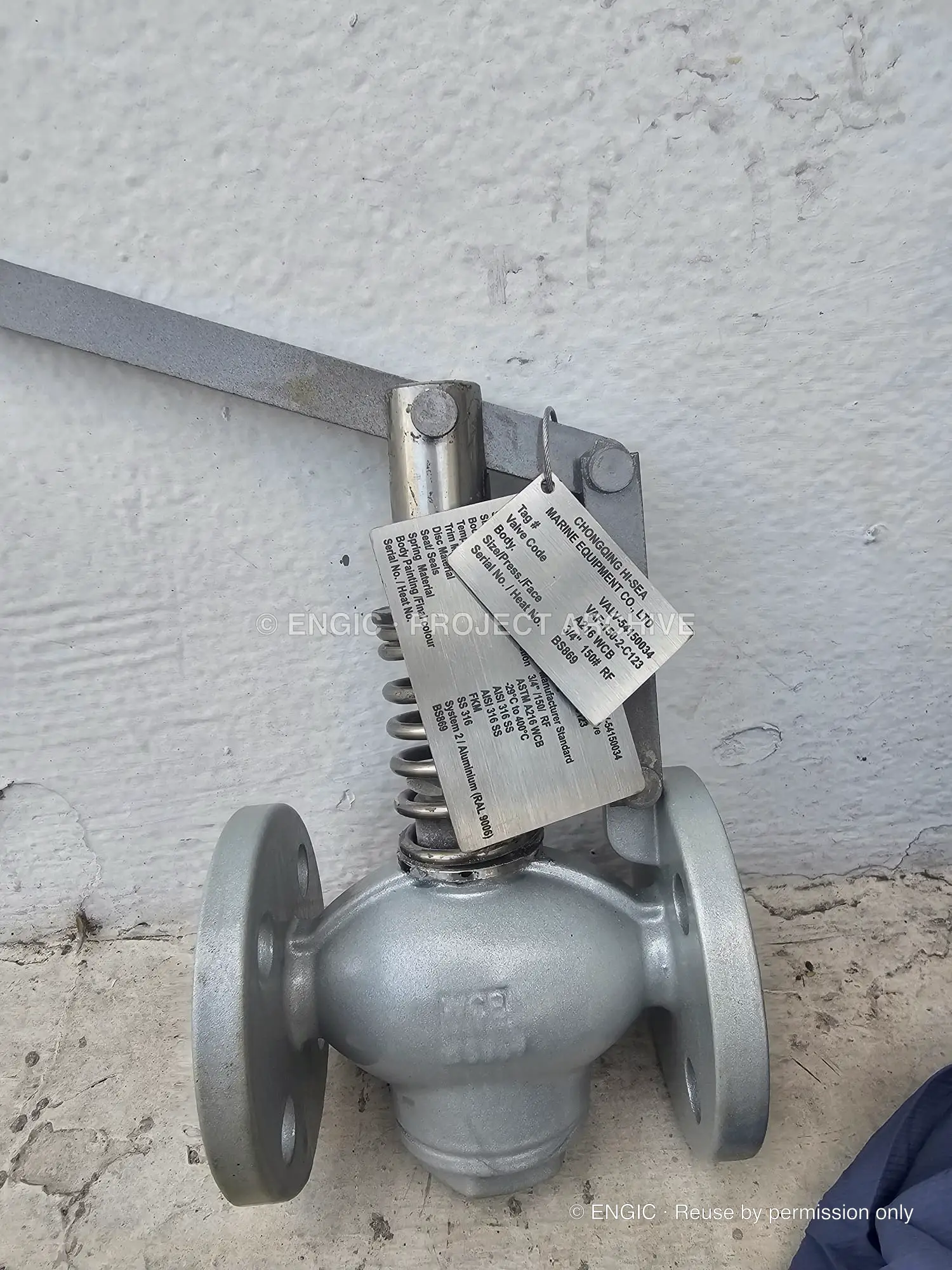 A compact silver flanged valve with an operating lever and identification tag