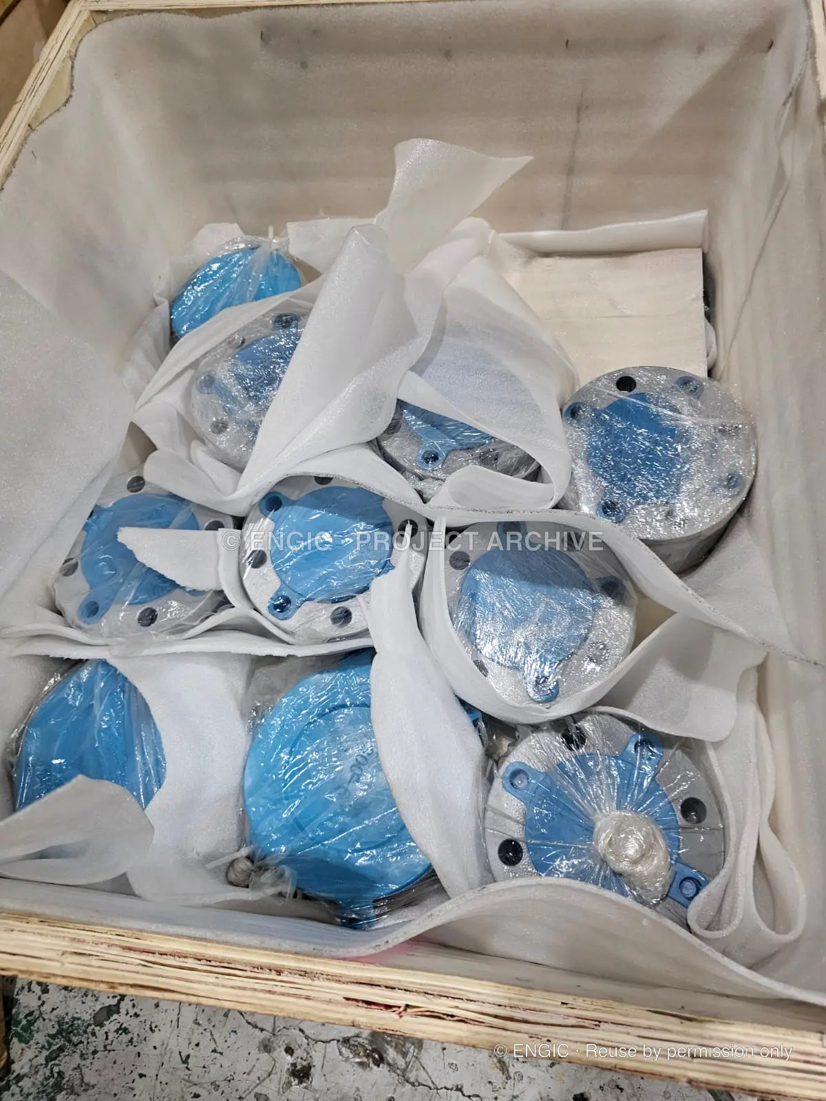 Blue-coated valve components individually wrapped and cushioned inside a timber case