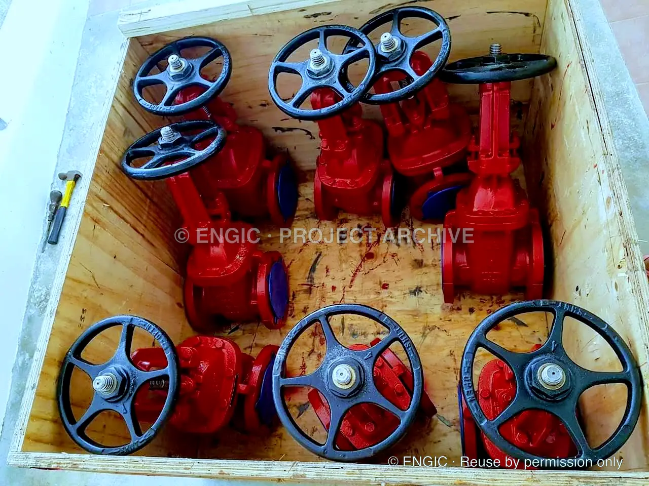 Red handwheel valves packed together in a timber crate